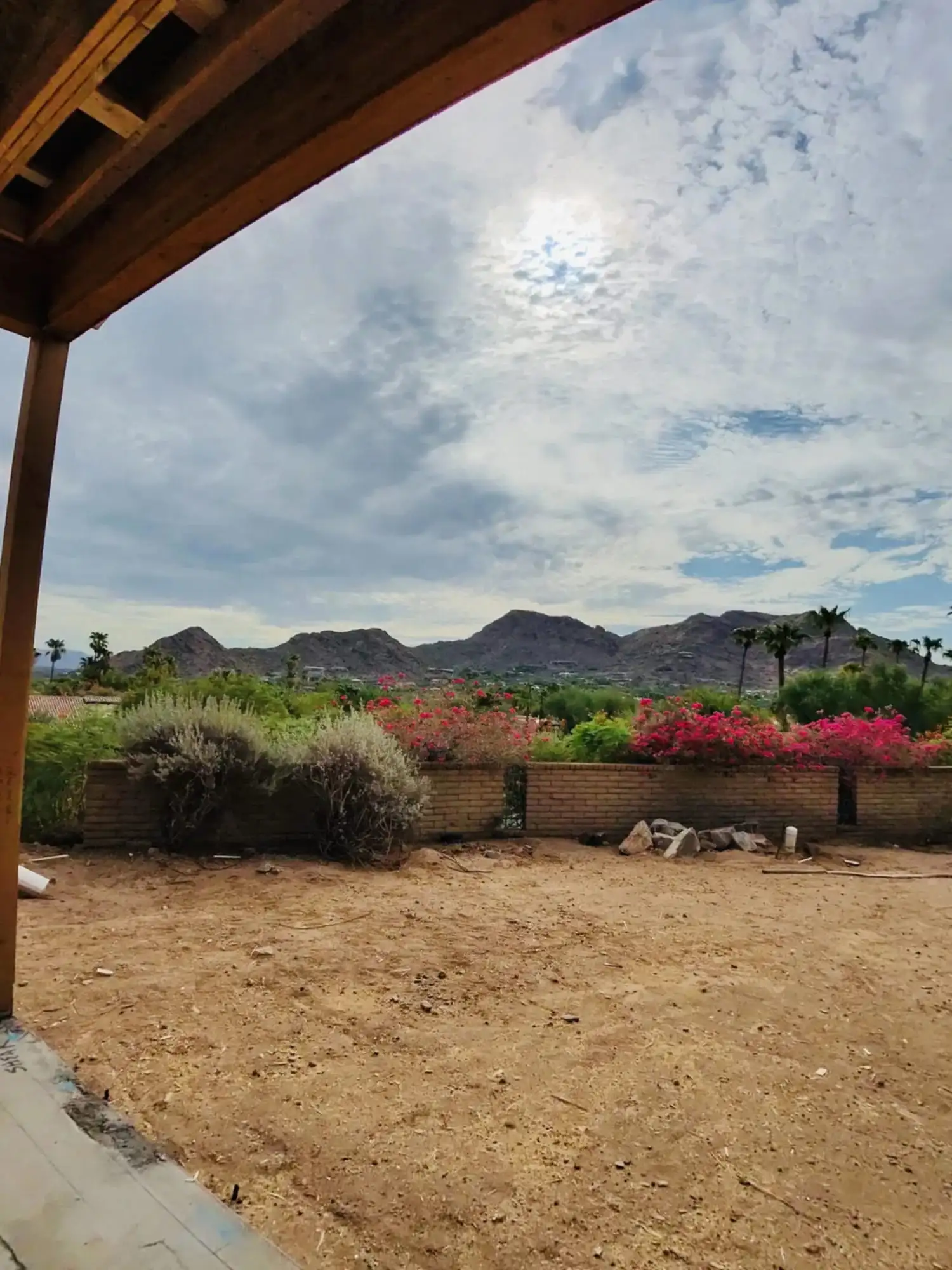 View out from under new patio framing at a West Valley job site, with desert mountains behind the block wall.